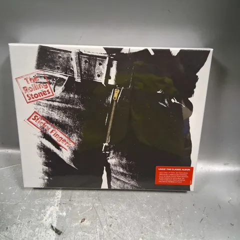 BOXED AND SEALED THE ROLLING STONES STICKY FINGERS UNZIP THE CLASSIC ALBUM INCLUDE; 3CD/DVD/7" VINYL SET, 120 PAGE COLLECTOR'S EDITION BOOK, 5 POSTCARD SET, PRINT AND POSTER AND MINI BAND MEMBER CUT O