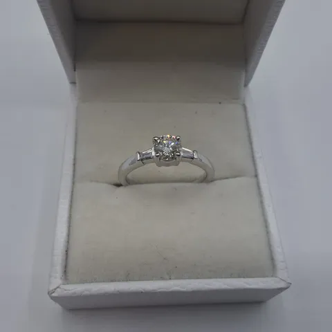 18CT WHITE GOLD RING SET WITH A NATURAL DIAMOND TO THE CENTRE AND A BAGUETTE TO EACH SHOULDER