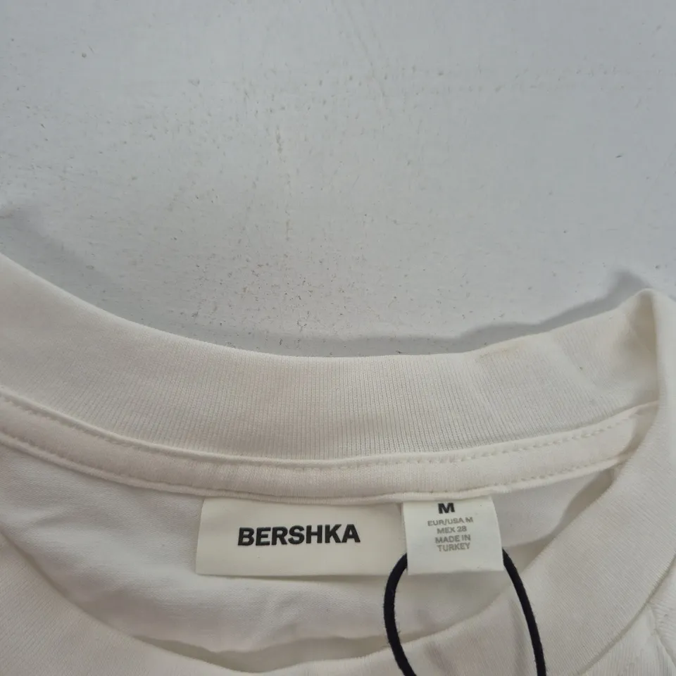 BERSHKA WHITE T-SHIRT WITH 'NOW & NEXT 83' GRAPHIC – SIZE M