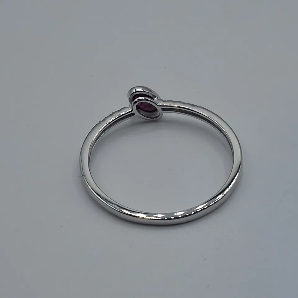 18CT GOLD RING WITH AN OFF-SET ROB OVER OVAL CUT RUBY AND NATURAL DIAMONDS TO EACH SHOULDER